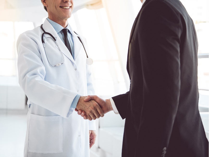 Photo of a doctor shaking hands with a man in a suit